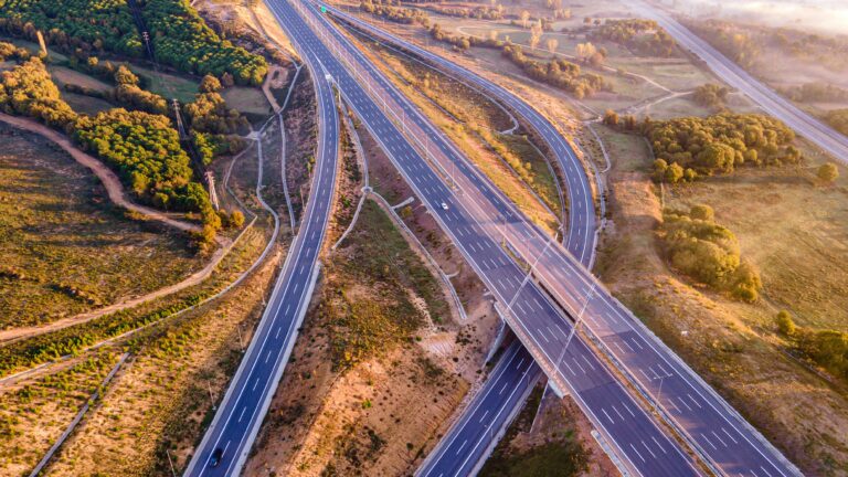 Stunning aerial photo of a highway interchange surrounded by lush countryside with morning light.